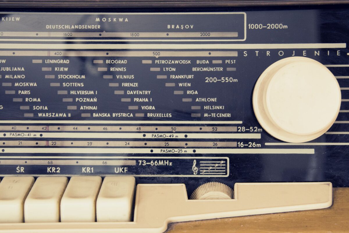 A detailed view of a vintage radio's tuning dial with city stations displayed.
