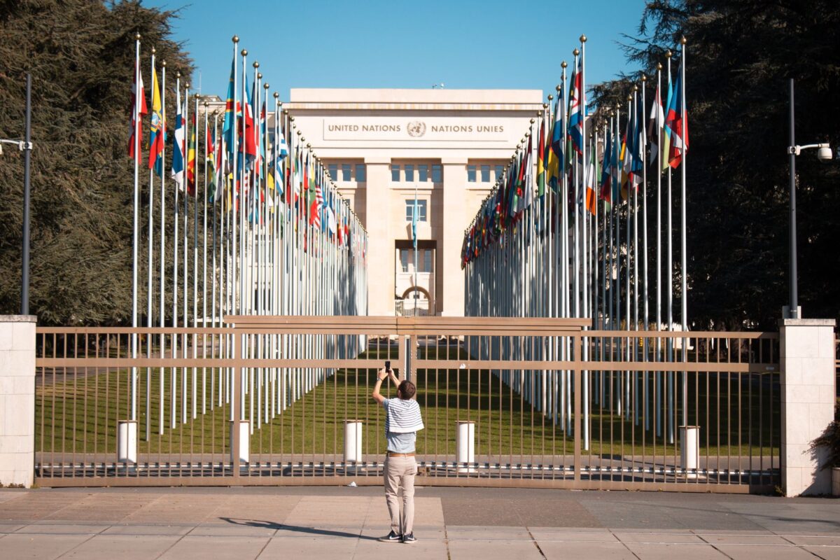 Man photographs the United Nations Office with international flags in Geneva, Switzerland.